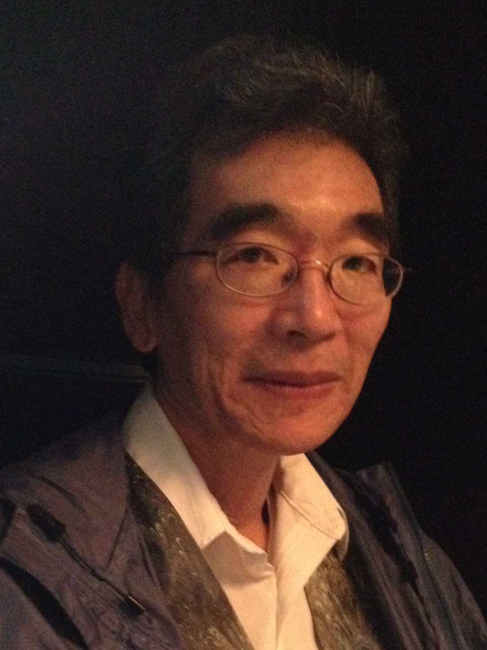 Color photograph of Dean Koga, in three-quarter profile, looking to the right.